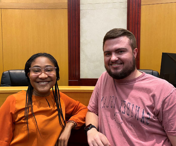 Students leaning against bench in courtroom of clinic.